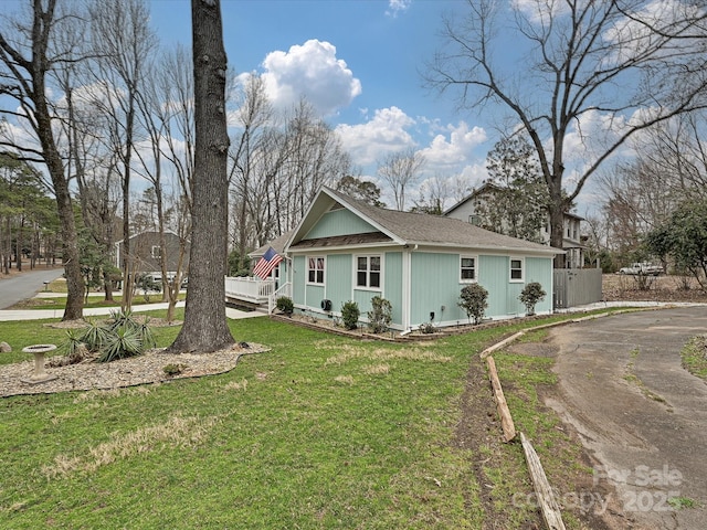 view of home's exterior with a yard, roof with shingles, and fence