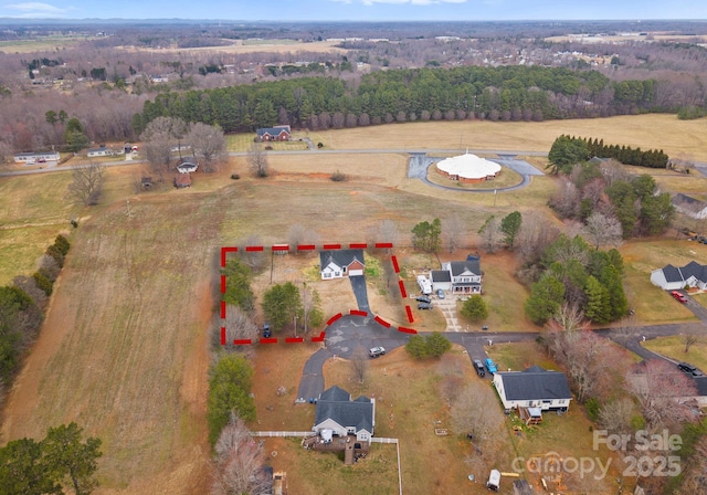 birds eye view of property featuring a rural view and a wooded view