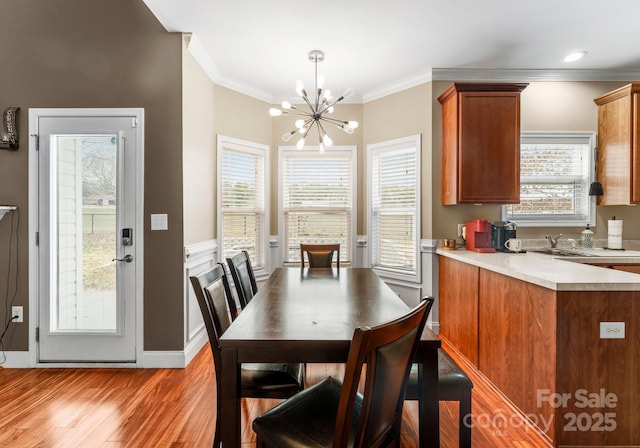 dining area with a notable chandelier, baseboards, light wood-style floors, and crown molding