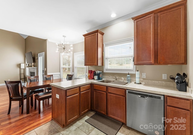 kitchen with light countertops, a wealth of natural light, a peninsula, stainless steel dishwasher, and a sink