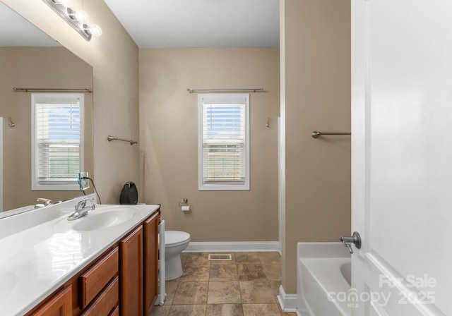 full bath featuring visible vents, baseboards, a washtub, toilet, and vanity