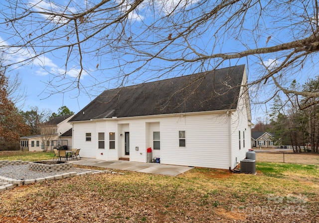 rear view of house featuring a patio area, a yard, and roof with shingles