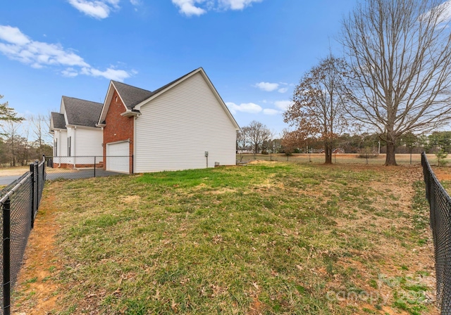 view of side of property with a garage, a lawn, and fence