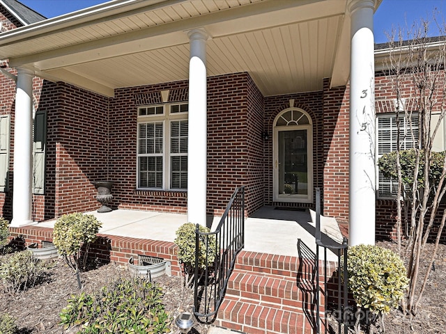 entrance to property featuring brick siding and a porch