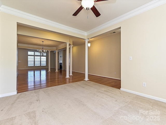 carpeted empty room with baseboards, ornamental molding, ceiling fan with notable chandelier, wood finished floors, and ornate columns