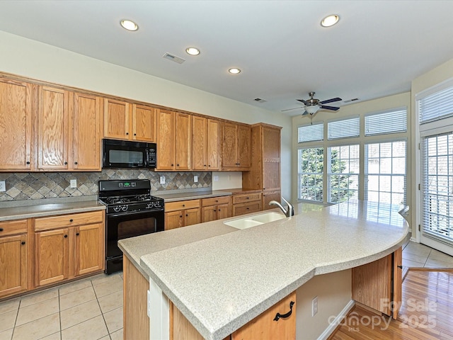 kitchen with visible vents, backsplash, a wealth of natural light, black appliances, and a sink