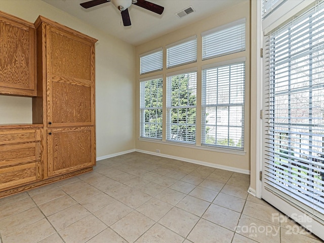 empty room with light tile patterned flooring, visible vents, baseboards, and a ceiling fan