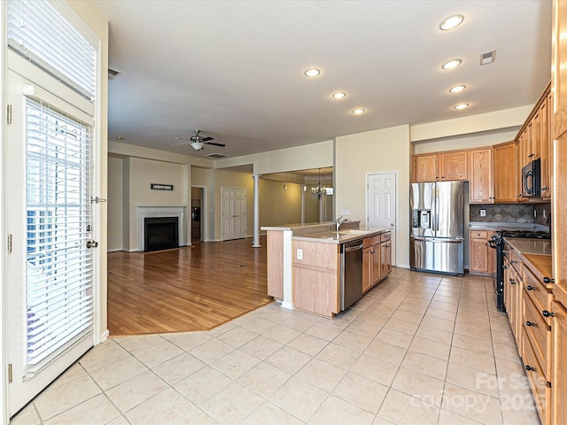 kitchen with ceiling fan with notable chandelier, black appliances, light tile patterned floors, and a fireplace