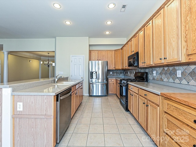 kitchen featuring light tile patterned floors, a center island with sink, a sink, black appliances, and tasteful backsplash