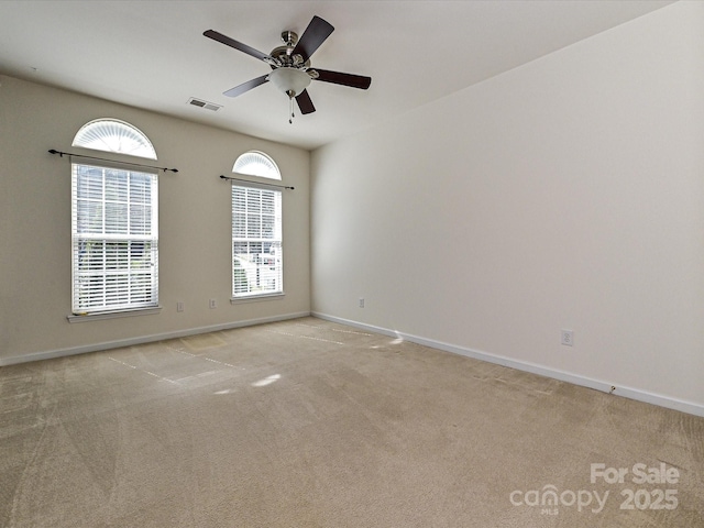 unfurnished room featuring visible vents, light carpet, baseboards, and ceiling fan