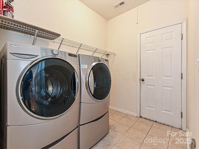 laundry area with light tile patterned floors, baseboards, visible vents, laundry area, and washer and clothes dryer