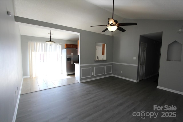 unfurnished living room with lofted ceiling, baseboards, a ceiling fan, and dark wood-style flooring