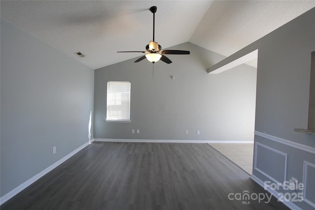 spare room with dark wood-style floors, lofted ceiling, visible vents, ceiling fan, and a textured ceiling