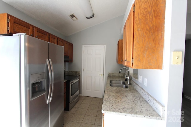 kitchen featuring stainless steel appliances, lofted ceiling, visible vents, light tile patterned flooring, and a sink