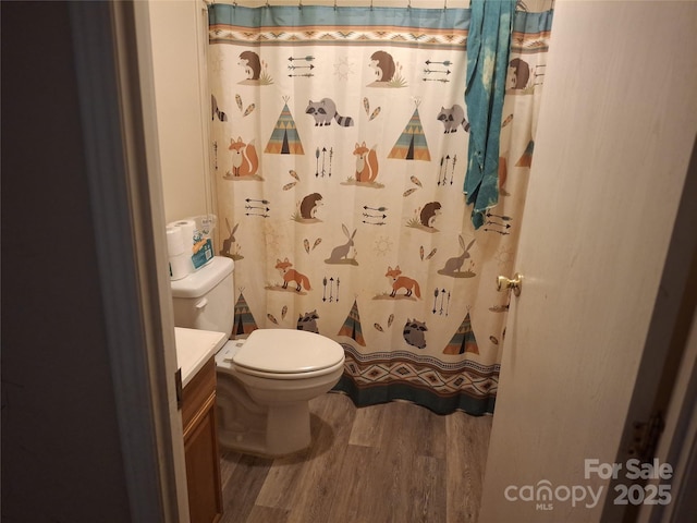 full bath featuring toilet, a shower with shower curtain, wood finished floors, and vanity