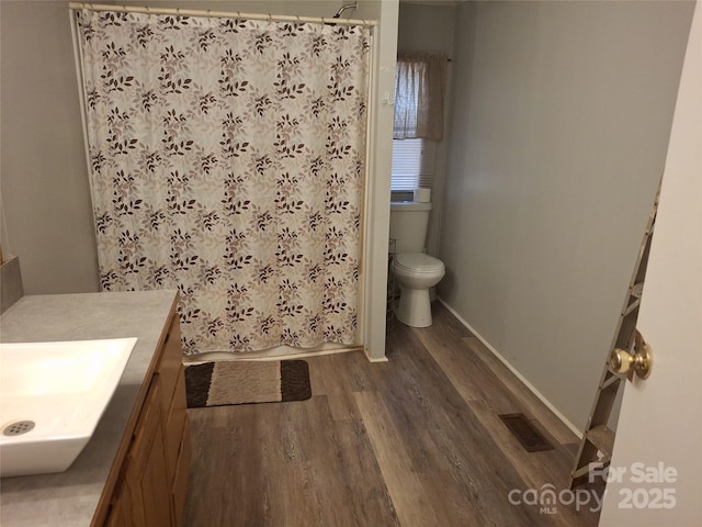 full bath with visible vents, a shower with shower curtain, toilet, vanity, and wood finished floors