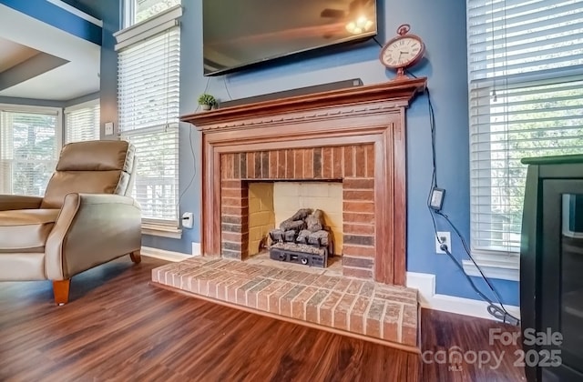 sitting room with a fireplace, dark wood-type flooring, and baseboards