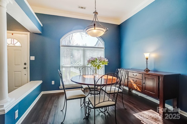 dining space with decorative columns, visible vents, dark wood-style flooring, and ornamental molding