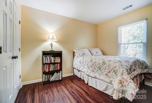 bedroom with wood finished floors, visible vents, and baseboards