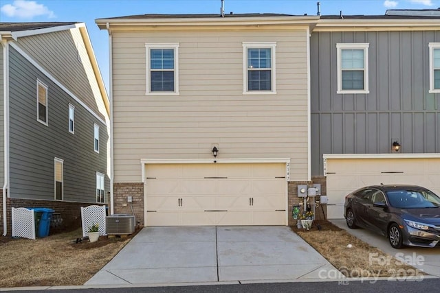 exterior space featuring brick siding, an attached garage, board and batten siding, cooling unit, and driveway