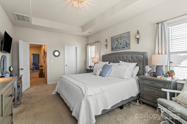 bedroom featuring baseboards, visible vents, a raised ceiling, and light colored carpet