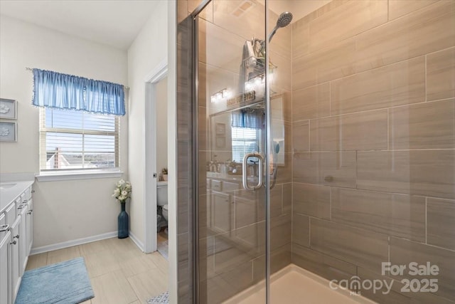 full bathroom featuring toilet, a stall shower, vanity, and baseboards