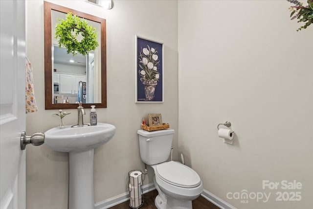 bathroom featuring a sink, wood finished floors, toilet, and baseboards