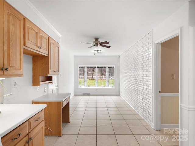 kitchen with light countertops, light tile patterned flooring, a ceiling fan, and brick wall