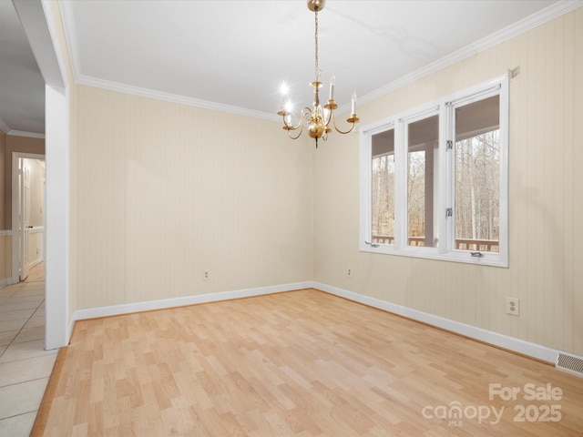 unfurnished room with baseboards, crown molding, an inviting chandelier, and wood finished floors