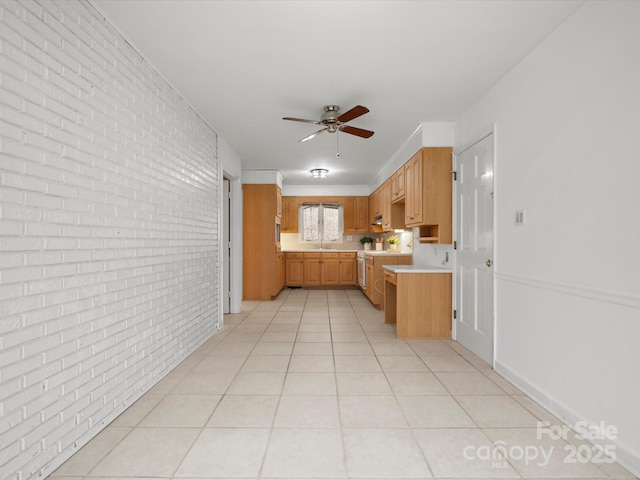 kitchen featuring a sink, brick wall, light countertops, light tile patterned floors, and ceiling fan