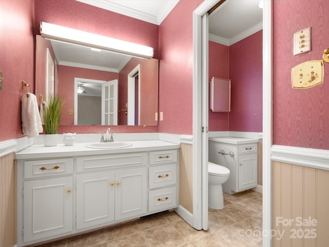 bathroom with tile patterned flooring, crown molding, a wainscoted wall, toilet, and vanity