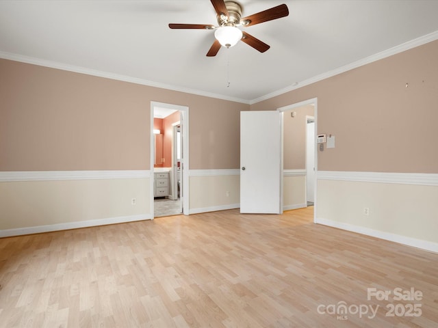 spare room featuring ceiling fan, light wood-type flooring, baseboards, and ornamental molding