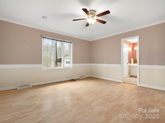 spare room with a ceiling fan, baseboards, visible vents, ornamental molding, and light wood-type flooring