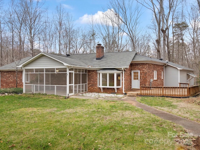 back of property with brick siding, a wooden deck, a lawn, a chimney, and a sunroom