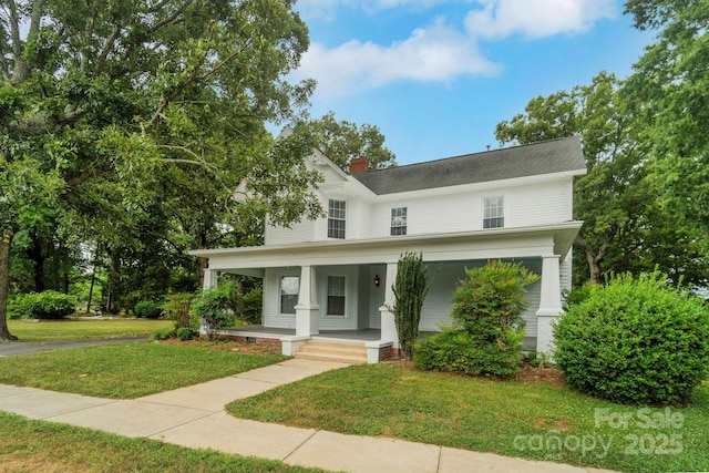 view of front facade with covered porch, a front lawn, and a chimney