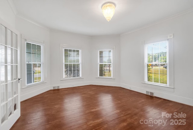 unfurnished room with wood finished floors, visible vents, and crown molding