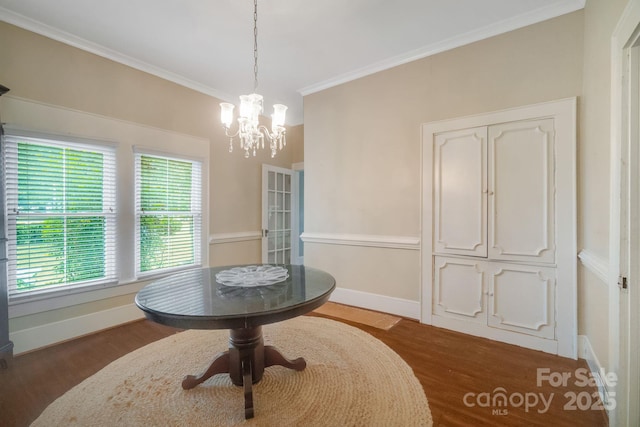 dining area featuring dark wood-style floors, ornamental molding, an inviting chandelier, and baseboards