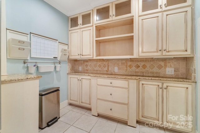 kitchen featuring light tile patterned floors, light stone counters, cream cabinets, and decorative backsplash