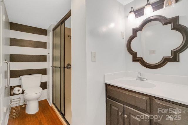 full bath with toilet, a stall shower, wood finished floors, and vanity