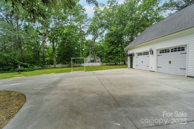 garage featuring driveway and fence