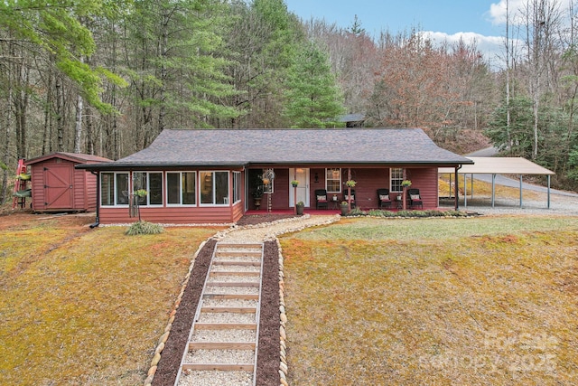 view of front of home featuring covered porch, an outdoor structure, a shed, a front lawn, and a view of trees