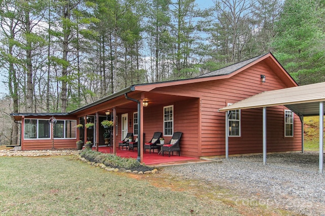 exterior space featuring a patio area, a sunroom, a carport, and a yard