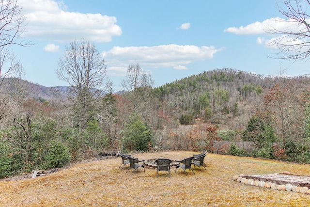 view of yard with a mountain view, a fire pit, and a forest view