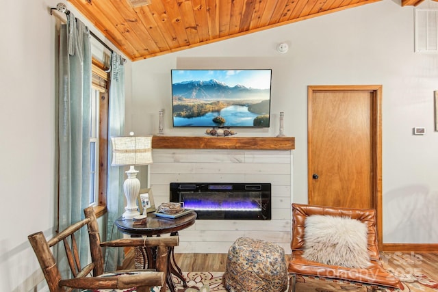 living area featuring lofted ceiling, visible vents, a glass covered fireplace, wood ceiling, and wood finished floors