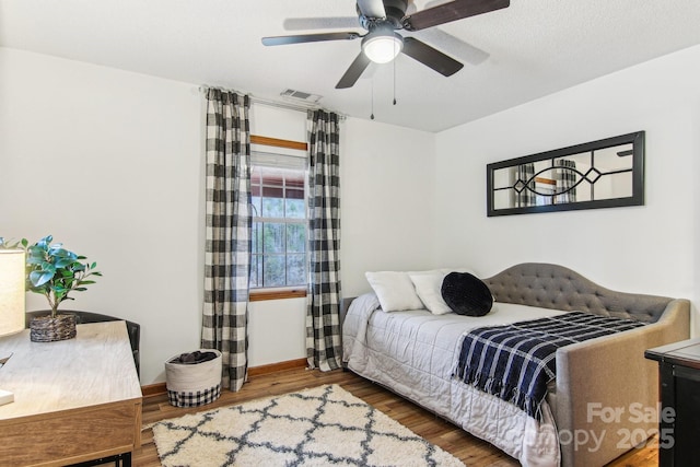 bedroom with baseboards, wood finished floors, visible vents, and a ceiling fan