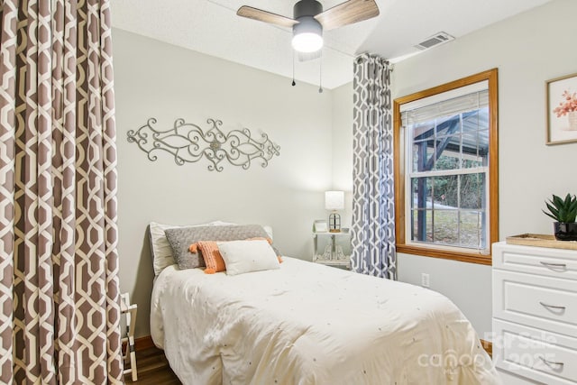 bedroom featuring ceiling fan, visible vents, and wood finished floors