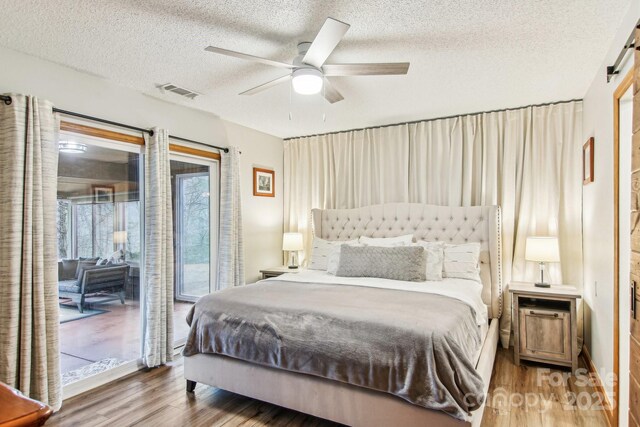 bedroom with a textured ceiling, ceiling fan, wood finished floors, visible vents, and access to outside