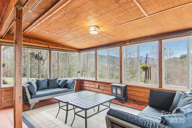 sunroom / solarium featuring wood ceiling and a wood stove