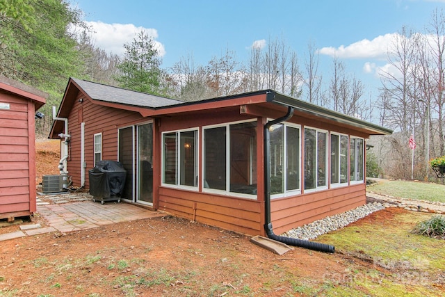 view of property exterior featuring central air condition unit, a sunroom, and a patio area