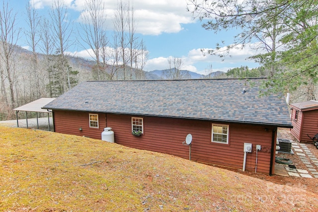 view of side of property with roof with shingles, a yard, and a mountain view